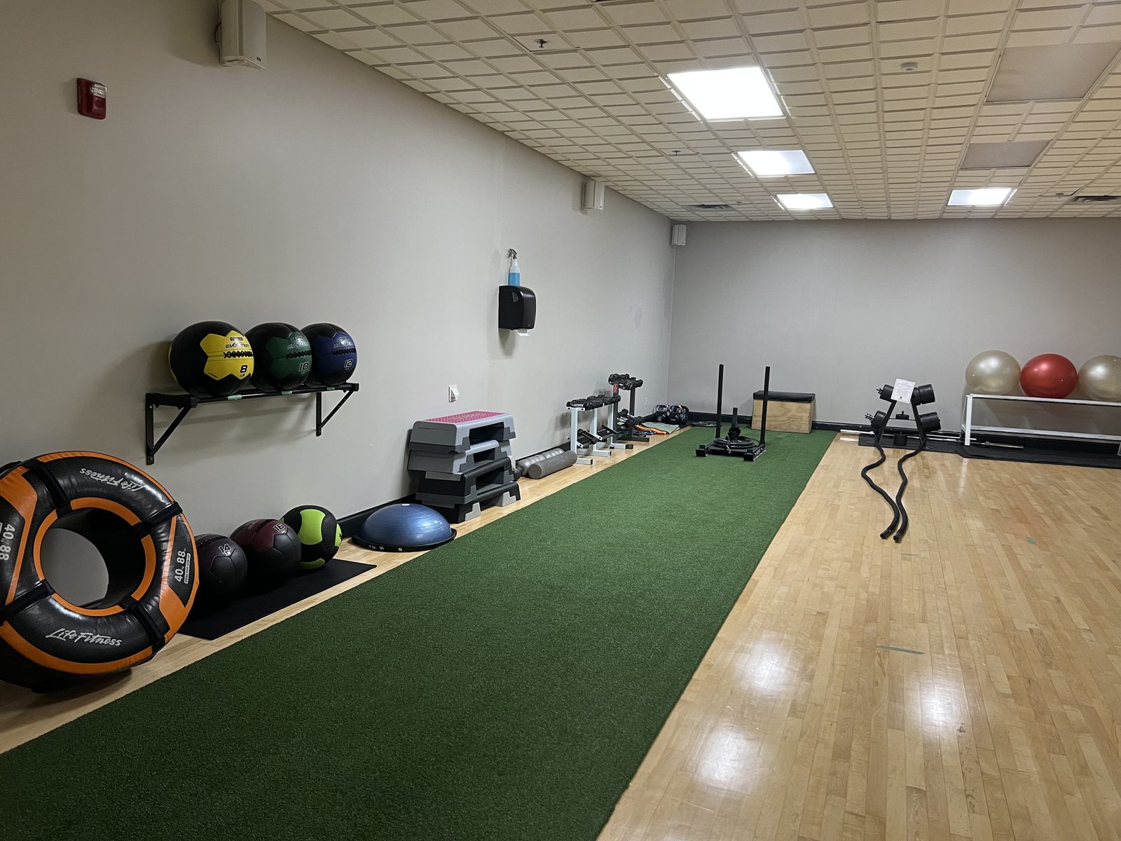 The functional fitness room at The Club — turf strip with sled, battle ropes, medicine balls and plyo boxes