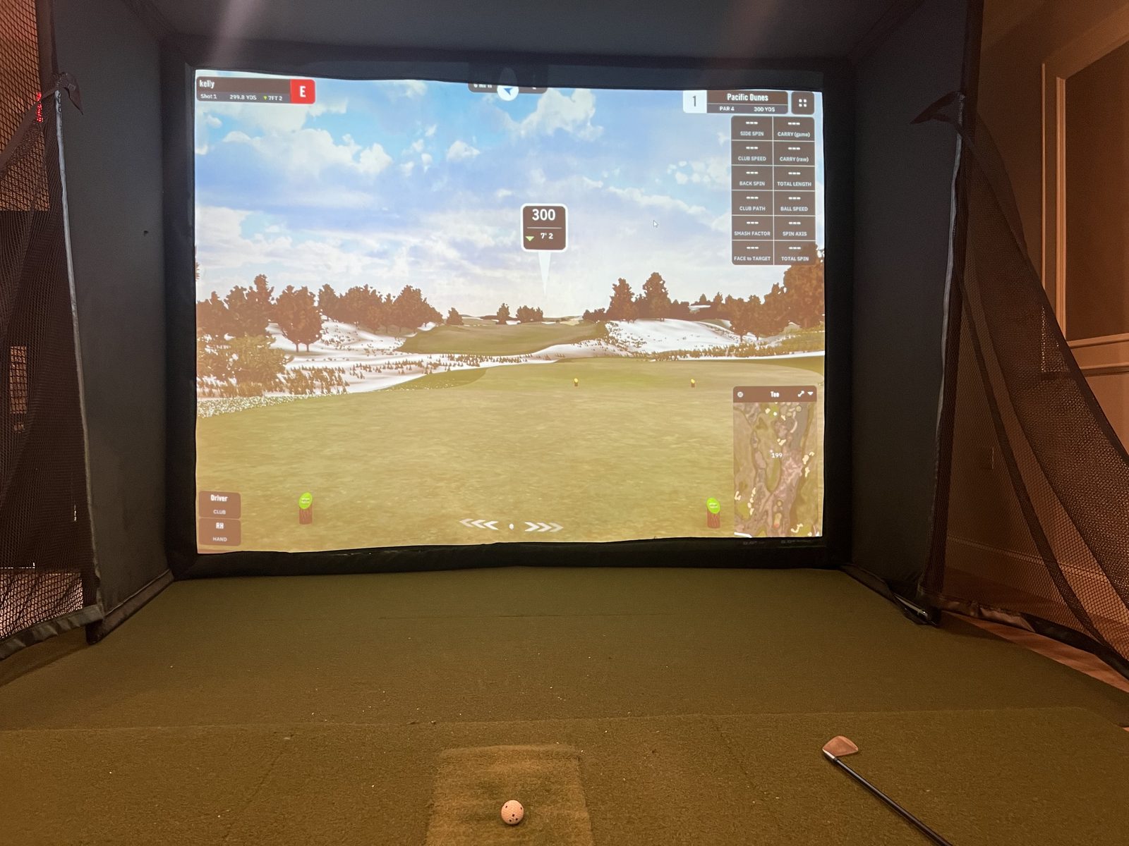 The golf simulator at The Club — a course on the projection screen, with a club and ball on the hitting mat