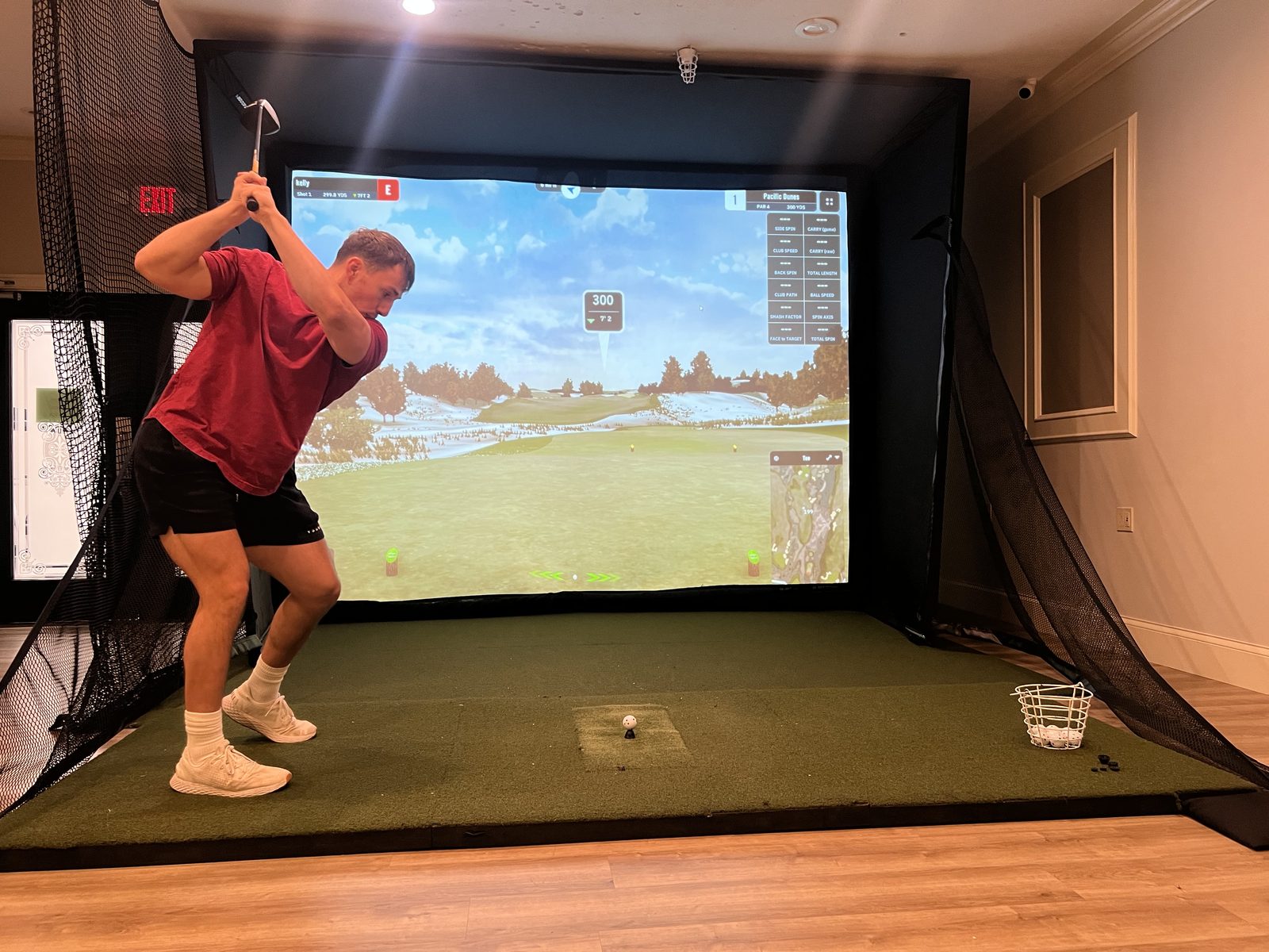 A golfer mid-backswing on the golf simulator at The Club