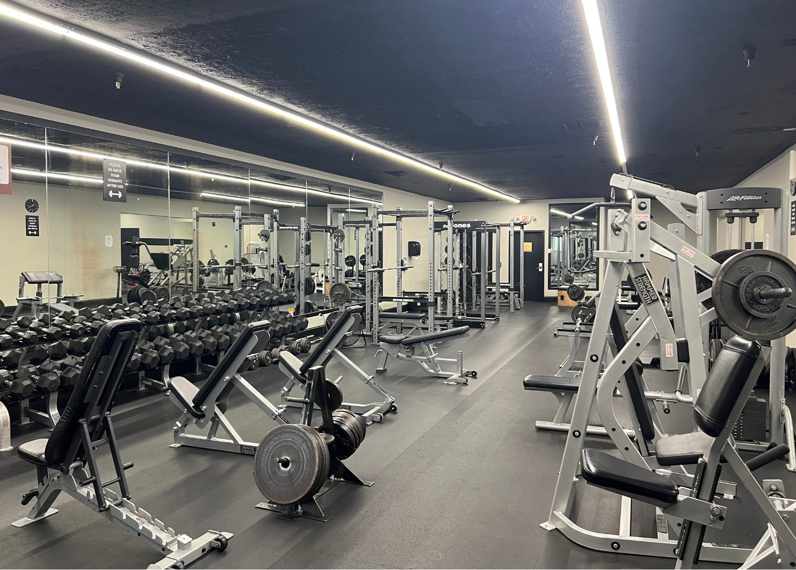 The weight room at The Club — dumbbells, benches, power racks and plate-loaded machines